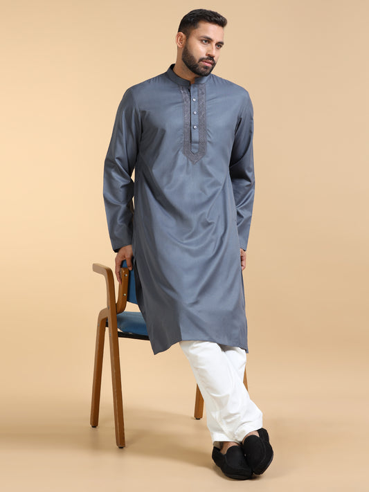 Man wearing a blue kurta with white pants on a beige background