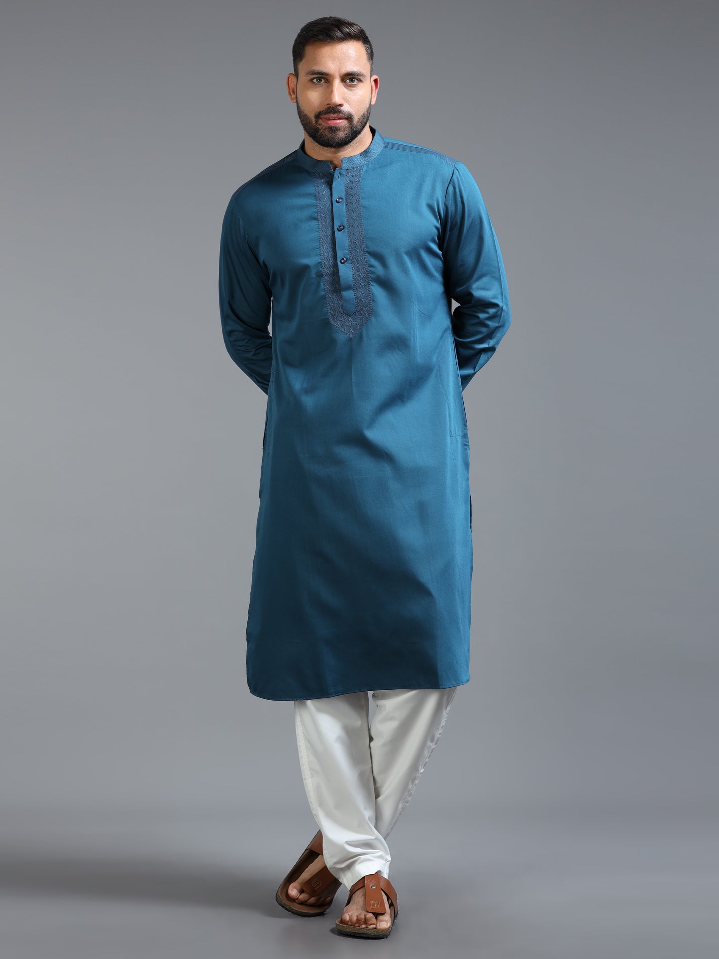 Man wearing a blue kurta with white pants on a gray background