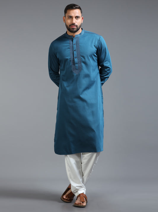 Man wearing a blue kurta with white pants on a gray background