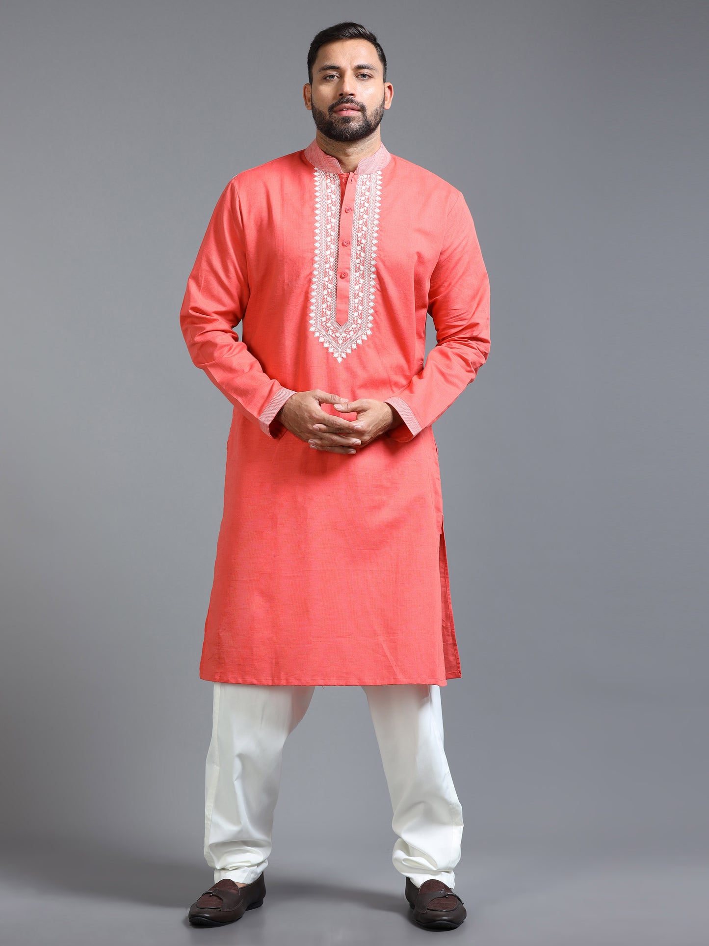 Man wearing a coral kurta with white embroidery on a gray background