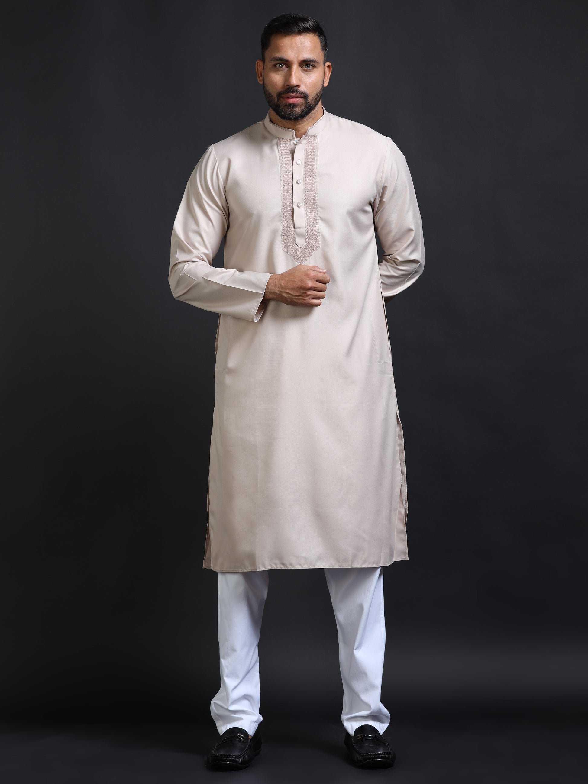 Man wearing a beige kurta with white pants on a black background