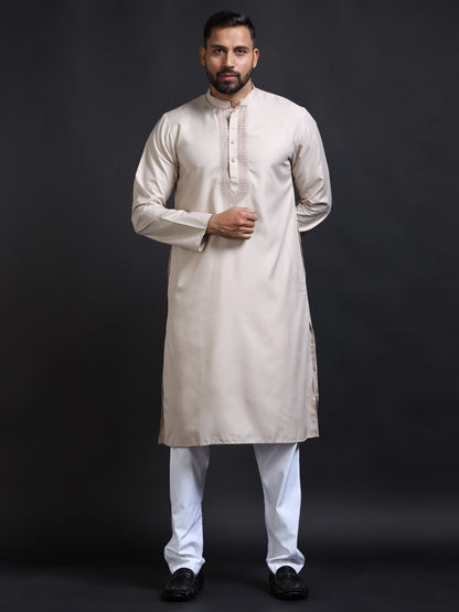 Man wearing a beige kurta with white pants on a black background