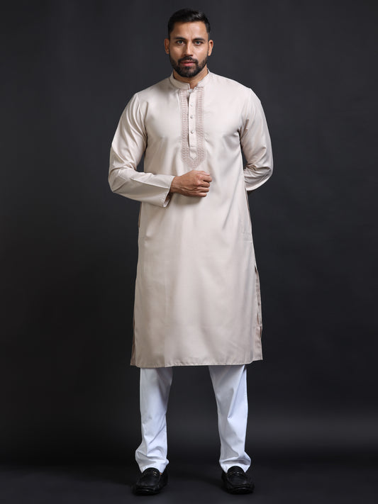 Man wearing a beige kurta with white pants on a black background