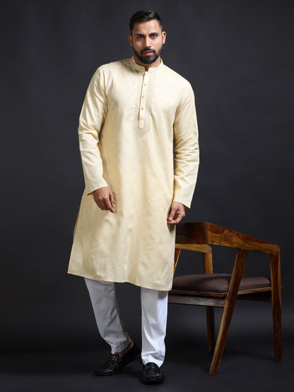 Man wearing a beige kurta with white pants against a dark background