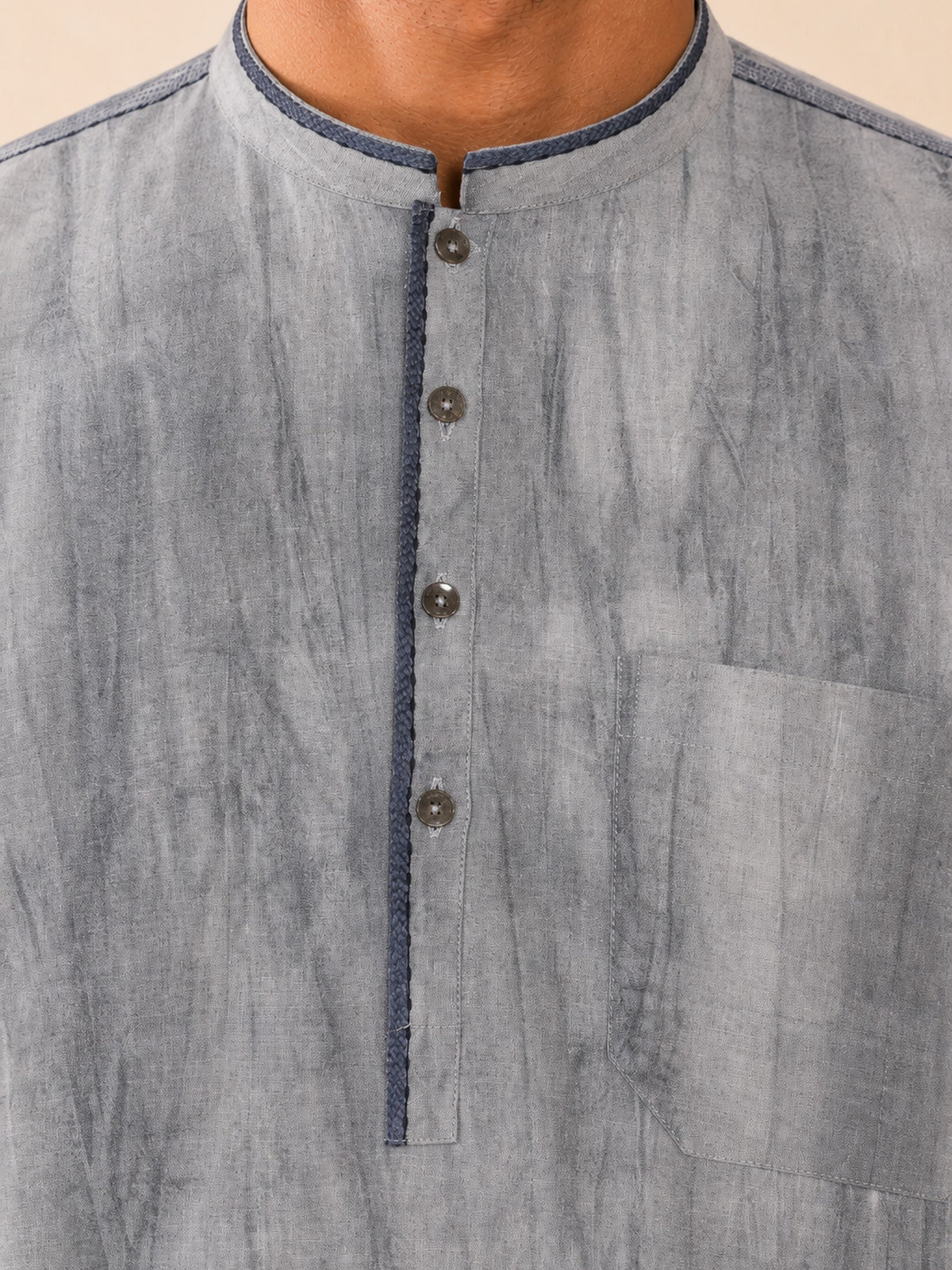 Close-up of the dark blue-grey collar, placket, metallic buttons and chest pocket on the grey smoked linen Pathani